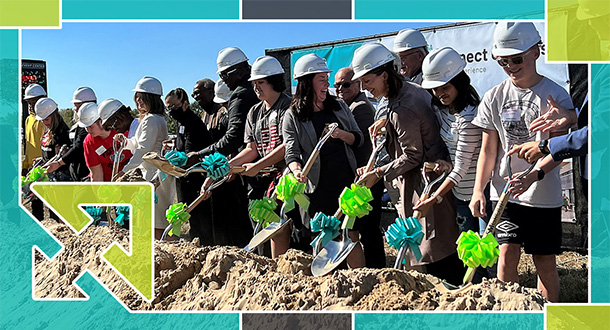  People in hard hats shovel dirt in ceremonial groundbreaking.